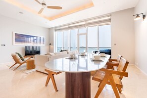 A modern living room with a large round table set for dining, a sofa, and a television.