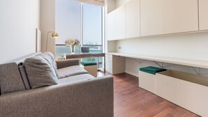 Uma sala de estar moderna com um sofá, um espaço de jantar com mesa e uma grande janela com vista para o mar.