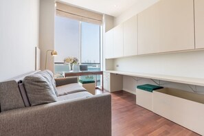 Un salon moderne avec un canapé, un coin repas avec une table et une grande fenêtre donnant sur la mer.