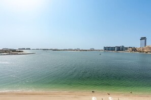 Eine Küstenstadt mit einer weiten Wasserfläche, einem Sandstrand und Hochhäusern im Hintergrund.