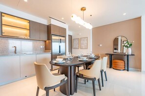 Un espace repas moderne avec une table ronde, six chaises et une cuisine intégrée équipée d’un réfrigérateur et d’un four.