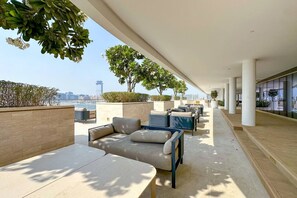 Eine moderne Lounge-Bereich im Freien mit Sitzgelegenheiten und viel Grün, mit Blick auf eine Stadtlandschaft.