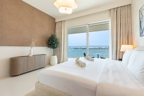 A hotel room with a large bed, a view of the sea, a balcony, and a modern design.