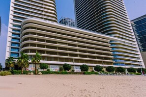 A modern hotel with multiple floors, a curved facade, and a beachfront location.