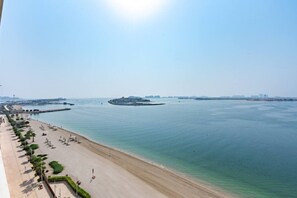 Een strand met helder water, een zandstrand en een eiland in de verte.