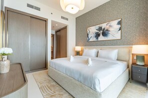 Un hotel moderno con una cama grande, una mesita de noche, un jarrón con flores y un cuadro en la pared.