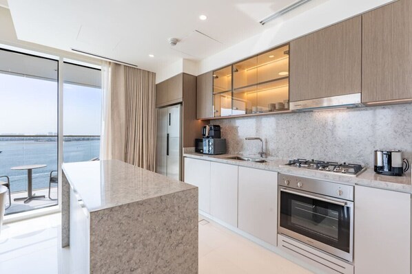 A modern kitchen with a large island, stainless steel appliances, and a view of the water.
