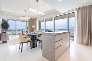 A modern dining area with a round table, chairs, and a view of the cityscape through large windows.