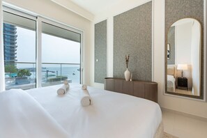 A hotel room with a large bed, a view of the sea, a balcony, and a modern design.