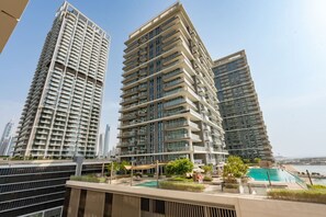 A high-rise residential building with multiple balconies, a rooftop pool, and a view of the city skyline.
