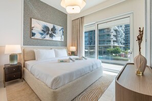 A modern hotel room with a large bed, two bedside tables, a large window with a city view, and a decorative vase on a side table.