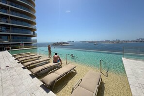 A poolside area with lounge chairs and a view of the sea.