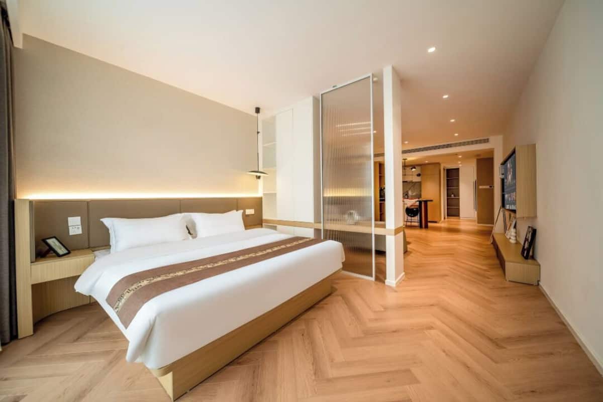 Una habitación de hotel moderna con una cama grande, una mesita de noche y un armario empotrado con puerta corredera.