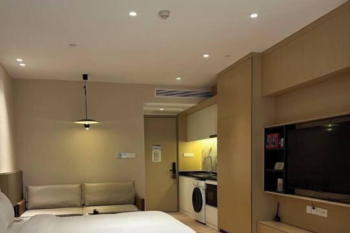 Habitación de hotel con dos camas, televisión, lavadora y una pequeña kitchenette.
