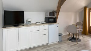 Una cocina compacta equipada con televisión de pantalla plana, cafetera, microondas y lavavajillas.