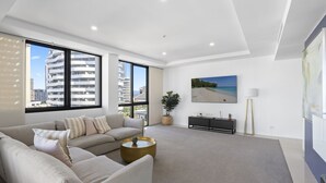 A modern living room with a large sofa, a coffee table, and a painting of a beach scene.