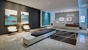 A modern reception area with a marble reception desk, seating area, and artwork on the walls.