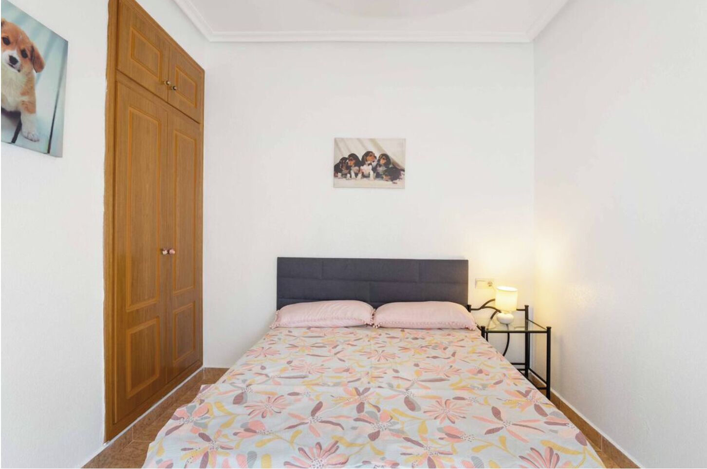 Quarto com cama, mesa de cabeceira, guarda-roupa de madeira e um quadro na parede.
