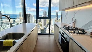 A modern kitchen with a large window, a sink, a stove, and wooden cabinets.