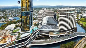 A modern hotel with a curved design, multiple floors, and a waterfront view.