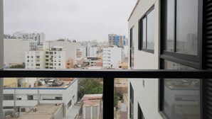 A view from a window overlooking a cityscape with various buildings, including residential and commercial structures. - w* | Chic 1BR Apartment in Miraflores (Lima)