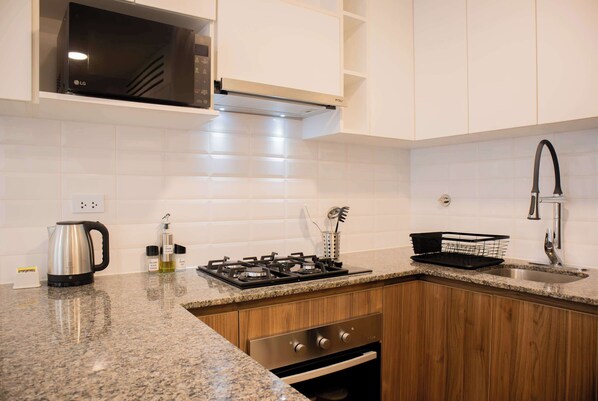 A kitchen with white cabinets, a stainless steel stove, a microwave, and a sink with a faucet.