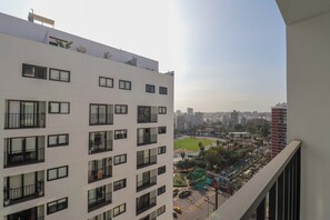 Un immeuble de grande hauteur doté de nombreux balcons et offrant une vue sur un paysage urbain composé d’immeubles et d’un parc.