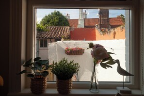 Janela com vista para um edifício com telhado telhado e parede branca.