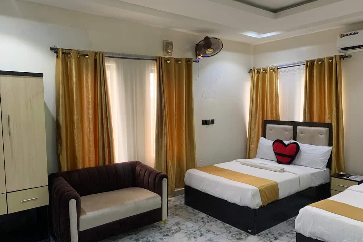 Una habitación de hotel con cama, sofá, armario y ventilador de techo.