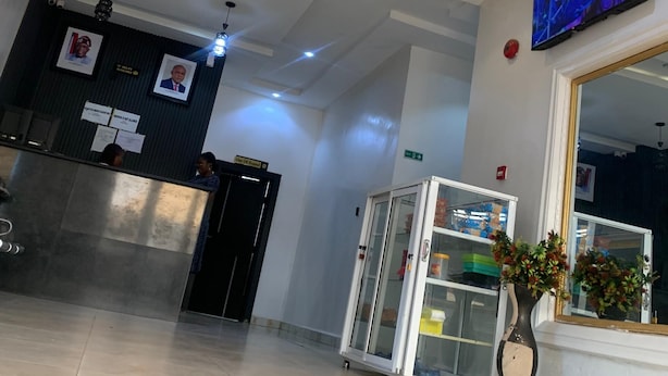 A hotel reception area with a modern design, including a reception desk, a digital screen, and a decorative ceiling structure.