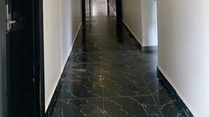 A hallway with a modern ceiling design, black marble flooring, and white walls.