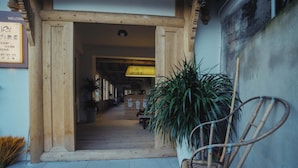 A wooden entrance with a signboard, a bamboo chair, and potted plants. - Shanye Lianglu (Leshan)