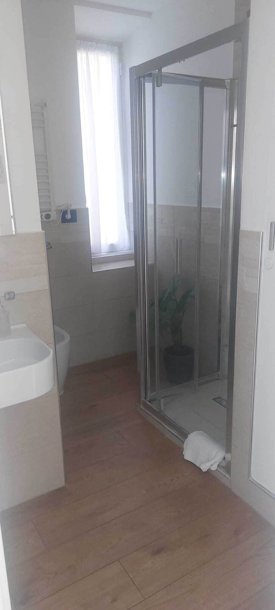Ein Badezimmer mit Duschkabine, Waschbecken und einem Fenster mit Vorhängen.