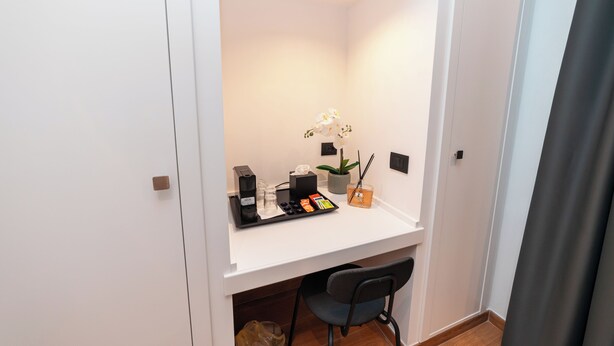 A small, well-lit room with a white desk, a chair, a potted plant, and a tray with various items. - Casa Palmeri (Rome)
