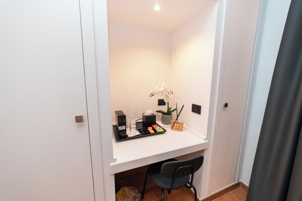 A small, well-lit room with a white desk, a chair, a potted plant, and a tray with various items. - Casa Palmeri (Rome)