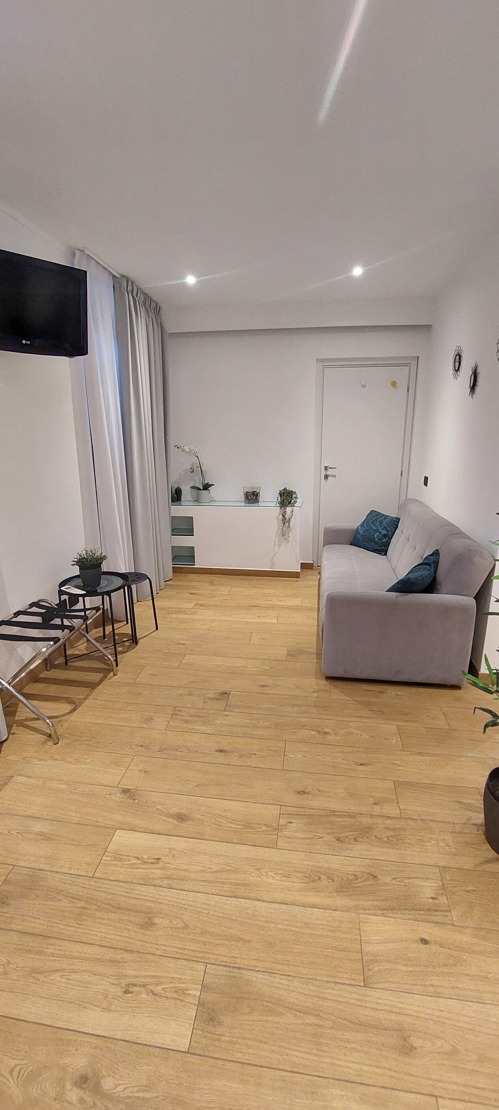 Un salon moderne avec un canapé gris, une petite table et un téléviseur fixé au mur.