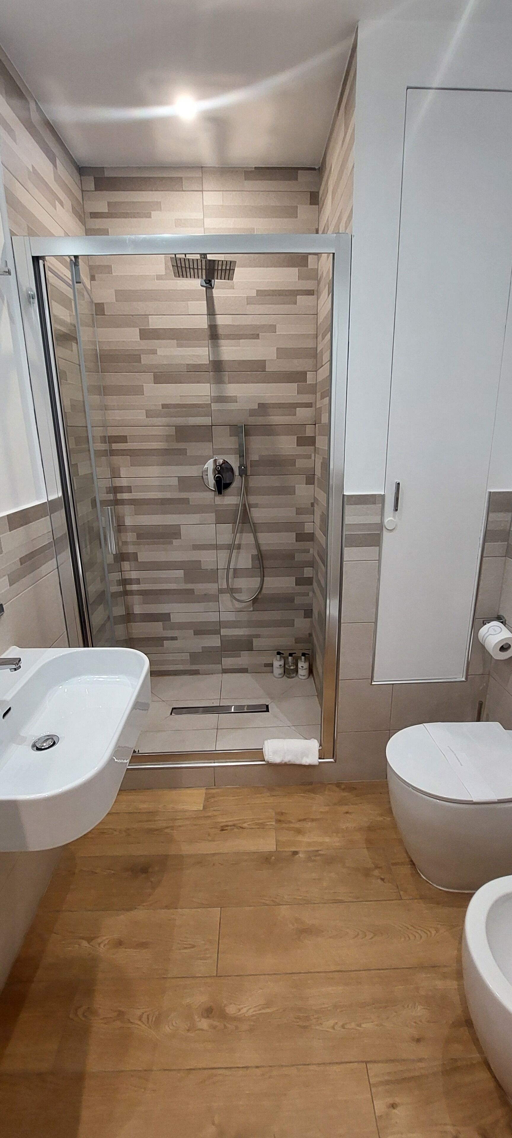 Un baño moderno con cabina de ducha, dos lavamanos y un inodoro.