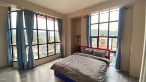 A bedroom with a bed, large windows, and a view of the city. - Verve Nepal (Kathmandu)