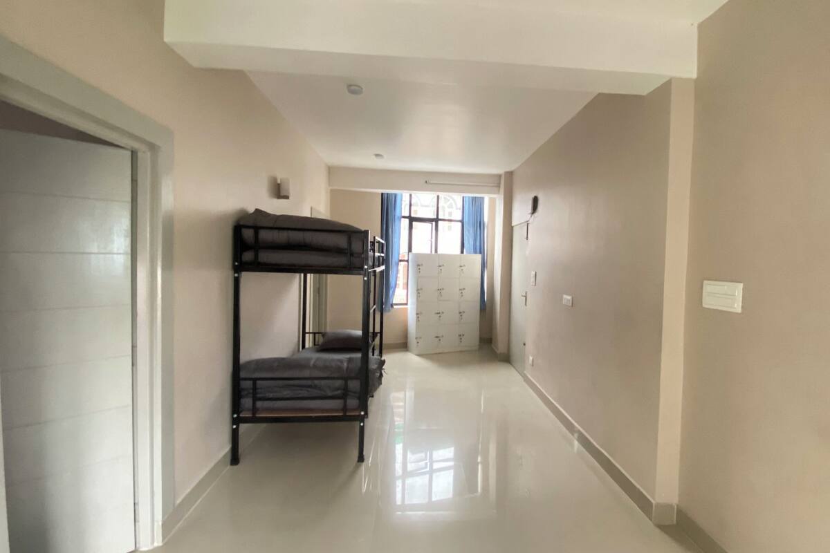 A hallway with bunk beds, a door, and a window with curtains.