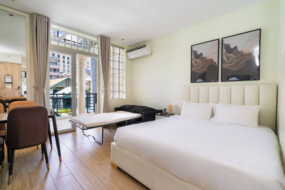 A hotel room with a bed, a desk, a chair, and a window with curtains.