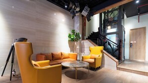 A modern interior with a yellow sofa set, a round coffee table, and a staircase leading to an upper level. - The Rixx Saigon Central - Next to Ben Thanh Market (Ho Chi Minh City)