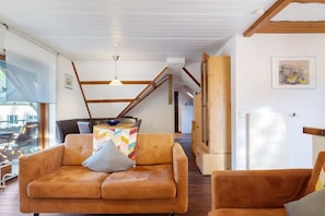 A modern living room with a sofa, a table with a bowl, and a staircase. - Apartment '70 sqm, 2 Bedrooms' with Mountain View, Balcony & Wi-Fi (Simonswald)