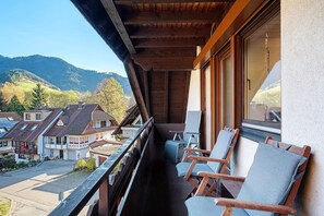 A balcony with wooden chairs and a view of a residential area and mountains. - Apartment '70 sqm, 2 Bedrooms' with Mountain View, Balcony & Wi-Fi (Simonswald)