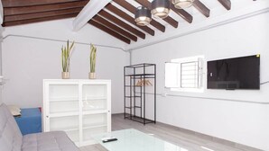A modern living room with a sofa, a glass coffee table, a white shelving unit, and a black metal stand. - Studio apartment in Almayate, next to the sea. (Almayate bajo)