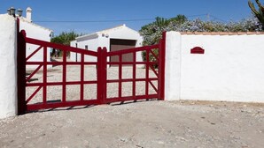 A gated entrance with a red gate, white walls, and a clear blue sky. - Studio apartment in Almayate, next to the sea. (Almayate bajo)