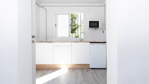 A modern kitchen with white cabinets, a wooden countertop, a built-in microwave, and a dishwasher. - Studio apartment in Almayate, next to the sea. (Almayate bajo)