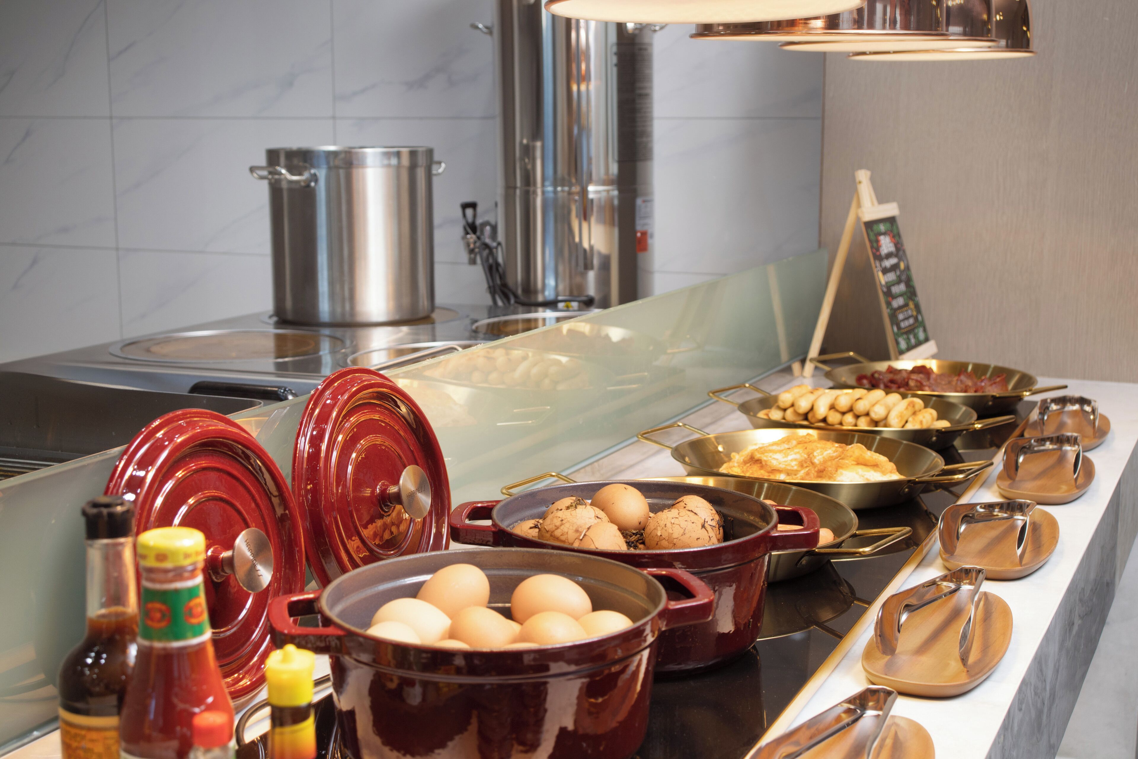 A buffet setup with various food items and cooking utensils.