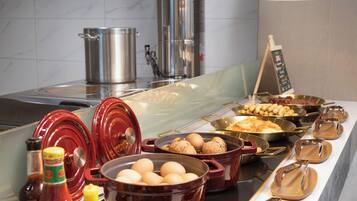A buffet setup with various food items and cooking utensils.
