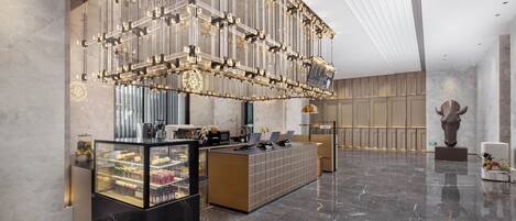 A modern lobby with a reception desk, a refrigerated display case, and a large decorative light fixture.