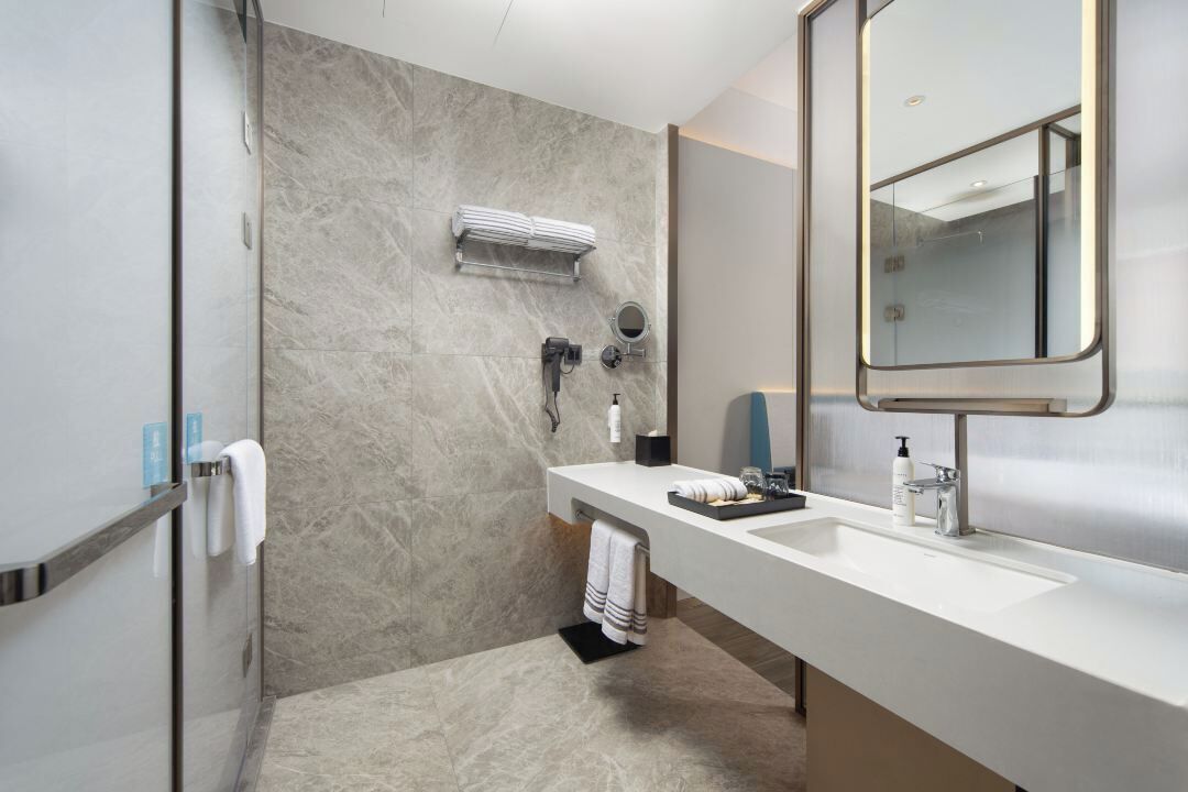 A modern bathroom with a shower, a sink, and a mirror.